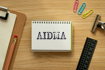 There is notebook with the word AIDMA. It is an abbreviation for Attention, Interest, Desire, Memory, Action as eye-catching image.