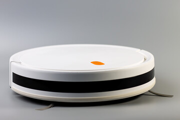 A modern white robotic vacuum cleaner with a black stripe, resting on a smooth grey surface. A smart home solution for automated cleaning. Photographed today, October 2, 2025, in Kamianske, Ukraine.

