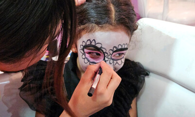 4-year-old Mexican girl is dressed in Catrina skull style makeup to celebrate the traditional Day of the Dead in Mexico