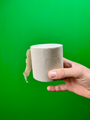 Hand holding toilet paper on green background