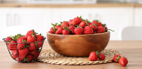 Bowl and basket with tasty strawberries on table in kitchen