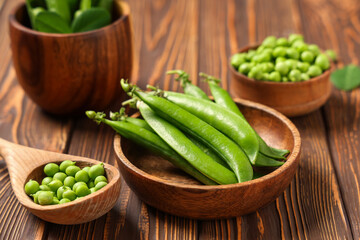 Bowl and spoon with fresh green peas on wooden background, closeup