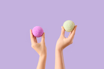 Female hands holding bath bombs on lilac background