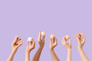 Female hands with different bath bombs and soap bars on lilac background