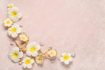 Beautiful plumeria flowers with starfishes and seashells on beige background