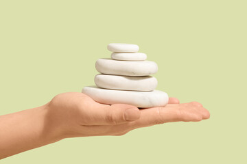 Hand with stack of pebbles on green background. Zen concept