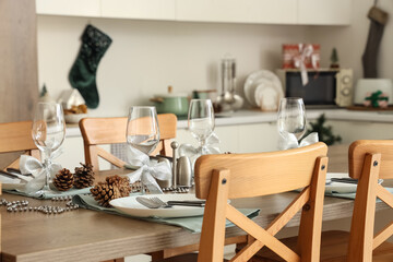 Christmas table setting with fir cones in kitchen