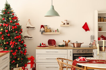 Interior of light kitchen with Christmas tree, counter and shelves
