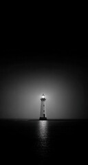 Monochrome lighthouse bathed in light over dark ocean waters. Intense beam highlights the structure