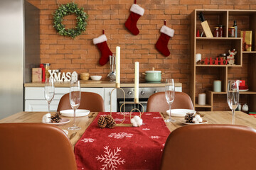 Christmas table setting with candles and fir cones in kitchen