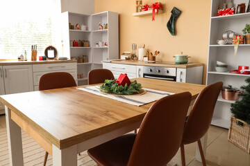 Interior of kitchen decorated for Christmas with counters and dining table