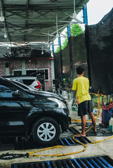 A car wash worker washing a car at a car wash station.