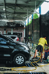 A car wash worker washing a car at a car wash station.