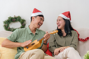 Christmas holiday, happy couple share love, enjoying winter season celebration at home with joy, man plays ukulele, woman laughs, festive cheer during christmas time