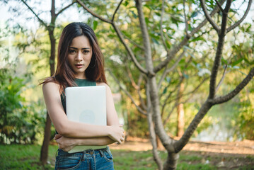 Fototapeta premium Close up businesswoman hand typing laptop drink black coffee cup in green garden cafe. Woman Hands love drinking hot coffee working from home. Business women with black coffee or hot chocolate cafe