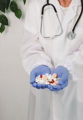 An elderly woman holds a mix of pills in her palms.