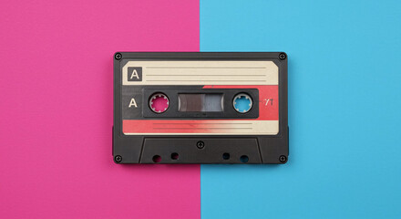 Fototapeta premium Retro audio cassette tape on a vibrant pink and blue background