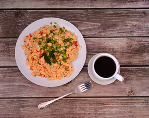 Fried egg omelette with tomatoes and decorated with chopped green onions and a sprig of parsley on a wooden table.