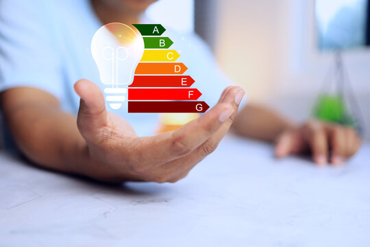 Energy labeling concept with hand holding a light bulb to define energy efficiency rating to indicate electric power or house hold appliance consumption save