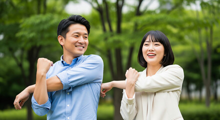 Smiling asian couple stretching arms in a green park