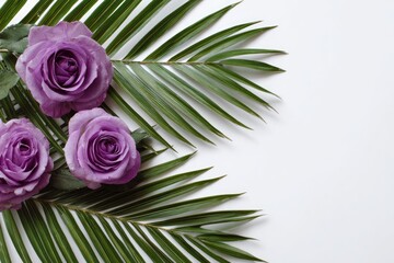 Three purple roses on palm fronds arranged against a white backdrop, creating a simple floral display