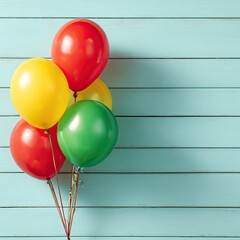 A cluster of vibrant balloons in red, yellow, and green against a light blue wooden wall