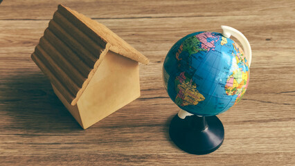 Miniature House Model and Globe Representing Global Real Estate Market, International Relocation, and World Property