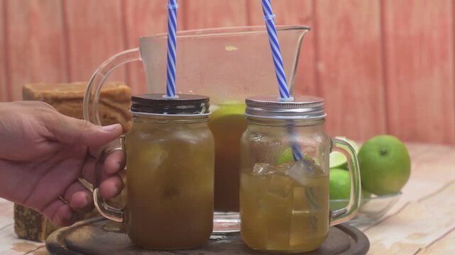 Chilled panela and lime beverage poured into a glass, styled on a rustic wooden table for serving.