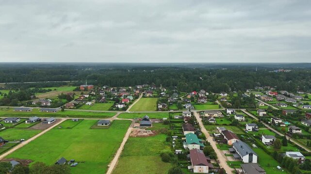 Drone pulls out over Ikskile revealing housing terrain forest edge and Daugava River while evoking the town&rsquo;s role as Livonia&rsquo;s first Christian center in Latvian history