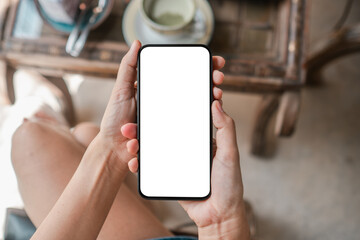 Close-up of hands holding a smartphone with a blank screen in a cafÃ©, ideal for app mockups or digital content.