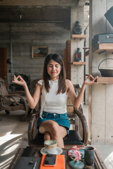 A young woman practices meditation in a stylish cafe, surrounded by rustic decor and natural light, creating a serene atmosphere.