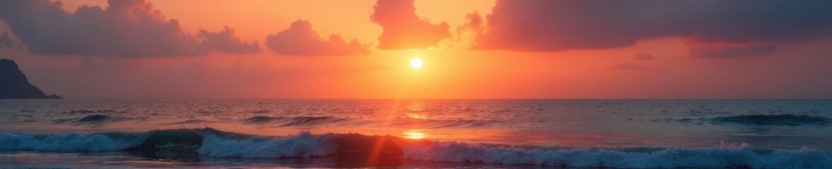 Sunset over placid ocean; gentle waves, hazy sky, coast, sunset