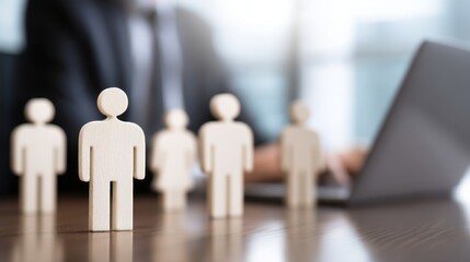 Human resources concept with wooden figures and business professional using laptop