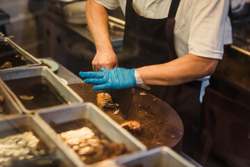 chef chopping grilled chicken with cleaver