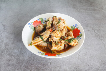 Spicy Thai chicken stir-fry with herbs in enamel bowl, rustic background