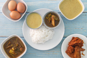Thai rice vermicelli “Khanom Jeen” with curry set and fried chicken, top view on blue wood