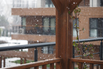 Snow falls gently on a balcony garden in a winter scene