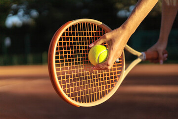 Woman tennis player tossing ball hitting racket at summer sunny outdoor court closeup