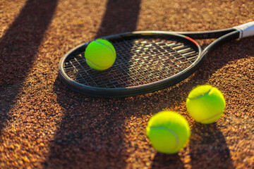 Tennis ball with rocket near grid at outdoor summer sunny court closeup