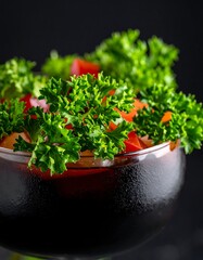 Curly parsley and diced tomatoes in a dark bowl