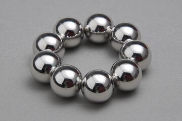 Polished metal ball bearings arranged in a symmetrical circle on gray surface