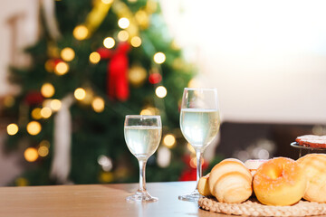 New Year Celebration. Sparkling drinks and pastries near a beautifully decorated Christmas tree.