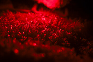 Abstract background of mysterious shiny red light on dark crystal texture. Glittering particles...