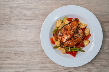 Grilled or Fried salmon steaks with fresh vegetables on plate. Top view on wooden table.