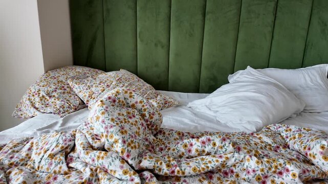 Bedding is rumpled and pillows are scattered in a bright room