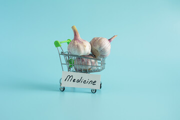 Garlic is a natural antiseptic and medicinal product. A garlic bulb in a cart in close-up on a light background and the inscription "medicine" on the side.