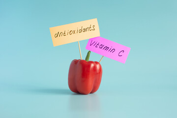 Sweet red peppers rich in vitamin C, as well as labels labeled vitamin C and antioxidants in close-up on a light background