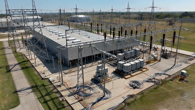 extensive and descriptive title about overhead drone shot of industrial high voltage electrical grid transmission substation complex