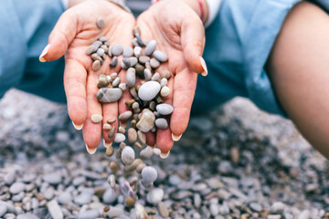 Pebbles Flowing from Woman is Hands on Rocky Beach Symbol of Release, Nature, and Balance