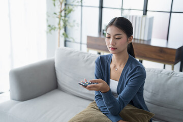 Asian woman Watching smart TV and using remote controller Hand holding television audio remote control at home with the remote control television